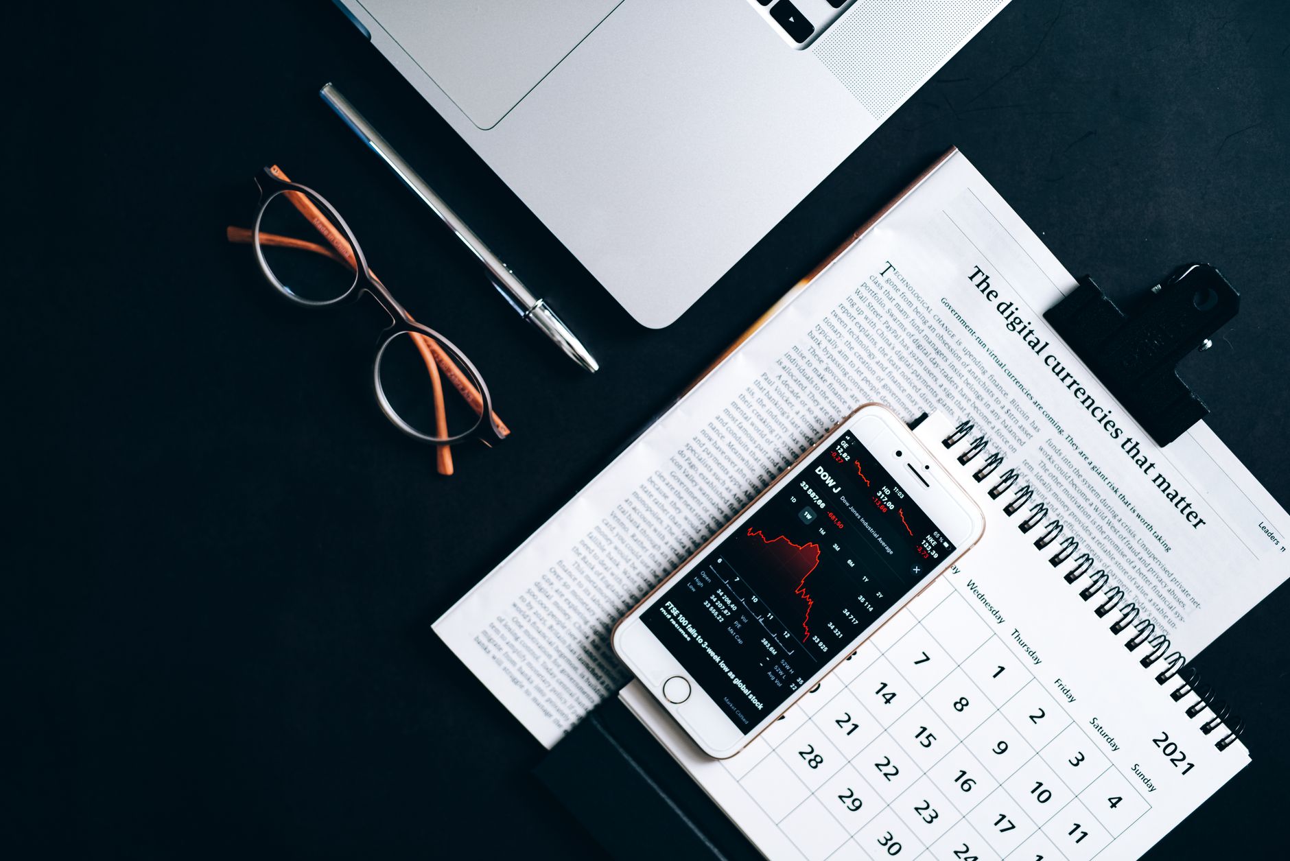 Calendário económico, jornal financeiro e gráfico da bolsa numa secretária